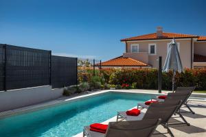 a swimming pool with chairs next to a house at VILLA ISTRA in Kaštelir
