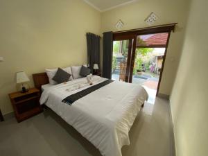a bedroom with a large white bed and a sliding glass door at Dika Homestay in Sidemen