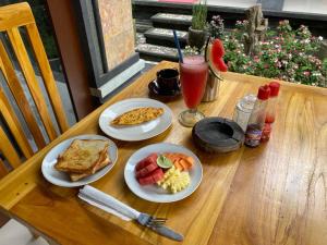 a wooden table with plates of breakfast food and a drink at Dika Homestay in Sidemen +69 photos