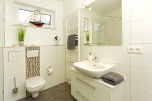 a white bathroom with a sink and a toilet at Kapitaensweg 2 Kajuete 06 in Ostseebad Karlshagen +12 photos