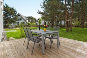 a table and chairs on a deck with a yard at Kapitaensweg 4 Koje 01 in Ostseebad Karlshagen +10 photos