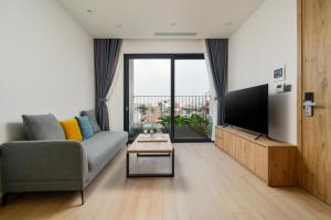 uma sala de estar com um sofá e uma televisão de ecrã plano em The Galaxy Home Doi Can Hotel and Apartment em Hanói