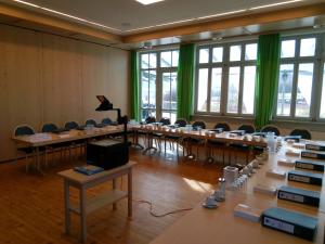 una stanza con file di tavoli e sedie con tende verdi di Deutenhof Hotel, Restaurant & Veranstaltung a Bad Abbach