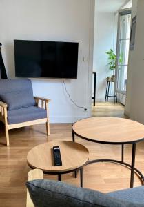 een woonkamer met 2 tafels en een flatscreen-tv bij Appartement au coeur de Paris in Parijs