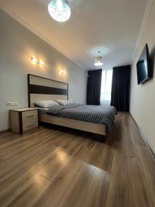 een slaapkamer met een groot bed en een houten vloer bij Затишні апартаменти TWO in Tsjernivsi