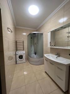 ein Badezimmer mit einer Waschmaschine und einem Waschbecken in der Unterkunft Затишні апартаменти TWO in Czernowitz