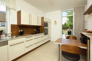 a kitchen with white cabinets and a wooden table at Kapitaensweg 17 in Ostseebad Karlshagen