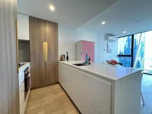 een keuken met witte werkbladen en een groot raam bij Avant CBD Cozy & Spacious 2BR Residences in Melbourne