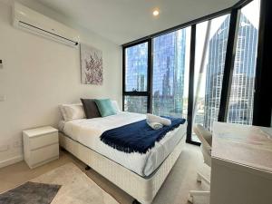 een slaapkamer met een bed en grote ramen bij Avant CBD Cozy & Spacious 2BR Residences in Melbourne