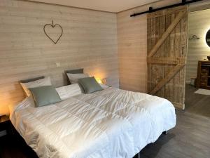 um quarto com uma grande cama branca com um coração na parede em Ambiance boisée Moustier em Stoumont