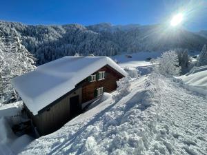 a building covered in snow with the sun in the background at Alpenchalet Piz Hüsli in Tschagguns