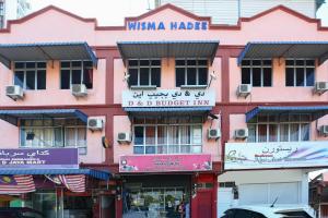 um edifício cor-de-rosa com placas na lateral em OYO 89755 D&d Budget Inn em Kota Bharu