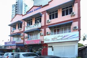 um edifício rosa com carros estacionados em frente em OYO 89755 D&d Budget Inn em Kota Bharu