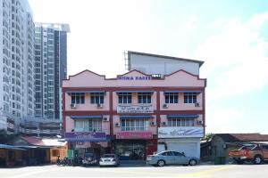um edifício rosa com carros estacionados em frente em OYO 89755 D&d Budget Inn em Kota Bharu