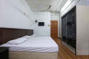 um quarto com uma cama grande e lençóis brancos em OYO 89755 D&d Budget Inn em Kota Bharu