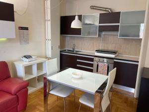 a small kitchen with a white table and a red couch at Tyche Suite Luxury in Lecce