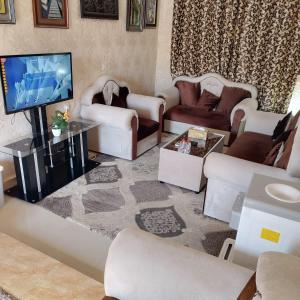 sala de estar con muebles blancos y TV de pantalla plana en العين الهيلي مصباح بيت 9, en Al Ain