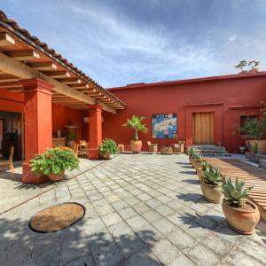 a red building with a patio with potted plants at Hotel La Casona de Tita in Oaxaca City