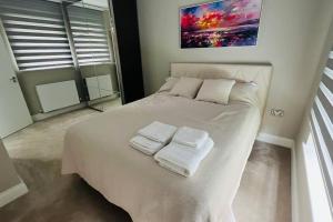 Un dormitorio con una cama blanca con toallas. en A house designed for you…, en Edmonton