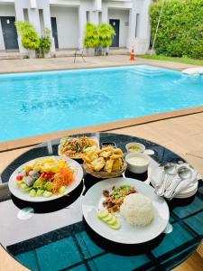a table with plates of food next to a swimming pool at Bualinn Resort in Nong Khai