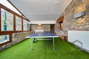 a ping pong table in a room with a stone wall at Chalet Can Noguer in Escaldes-Engordany