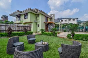 a yard with chairs and tables in front of a house at Villan Villa Luxurious Mountain View Biggest Pool in Lonavala
