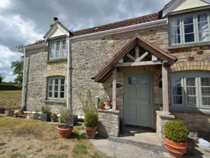 a stone house with a green door and potted plants at 2 Bed in Wedmore 53989 in Wedmore