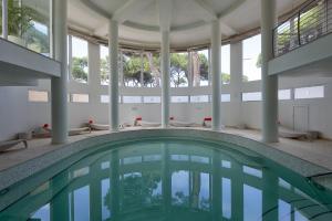 a swimming pool in a building with a large window at Hotel Terme Marine Leopoldo II TERME & SPA in Marina di Grosseto