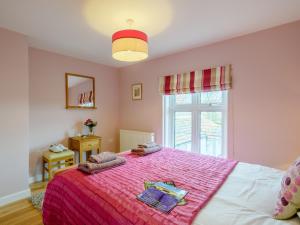 ein Schlafzimmer mit einem großen Bett mit einer rosa Decke in der Unterkunft 3 bed property in Weybourne Norfolk KT069 in Weybourne