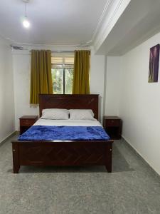 sypialnia z łóżkiem z niebieską kołdrą i oknem w obiekcie Ingrid's Place - Namugongo w mieście Namugongo