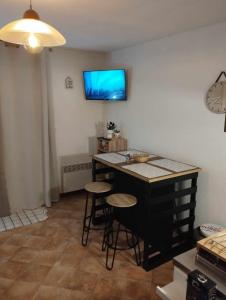 een keuken met een bar met krukken en een tv aan de muur bij Charmant studio avec terrasse in Praz-sur-Arly