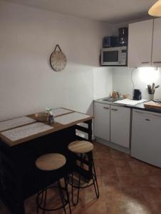 een keuken met een aanrecht en krukken en een klok aan de muur bij Charmant studio avec terrasse in Praz-sur-Arly