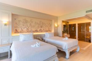 a bedroom with two beds and a painting on the wall at The Hotspring Beach Resort & Spa - SHA Extra Plus in Natai Beach