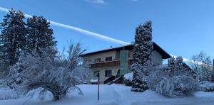 a building covered in snow with trees in front of it at Dorfpension Mariahilfberg in Gutenstein