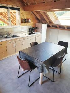 een keuken met een zwarte tafel en stoelen bij WhispeRive Lodge - le vert aux bords de rive in Le Bourg-dʼOisans