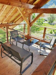 eine Veranda mit Stühlen und einem Tisch auf einer Holzterrasse in der Unterkunft WhispeRive Lodge - le vert aux bords de rive in Le Bourg-dʼOisans