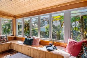 a room with windows and a couch with a sink at Aranui palms - Mapua Holiday Home in Mapua