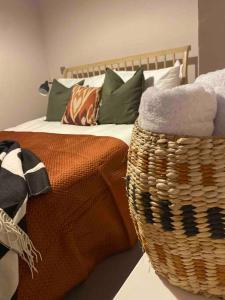 a bedroom with a bed with pillows and a basket at Boutique, weaver’s cottage. Views in Bradford on Avon