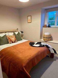 a bedroom with a bed with an orange blanket on it at Boutique, weaver’s cottage. Views in Bradford on Avon