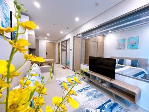 a living room with a television and yellow flowers at The Song WinHome Apartment in Vung Tau