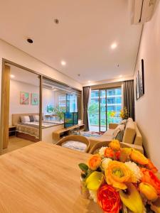 The Song WinHome Apartment في فنغ تاو: غرفة معيشة مع سرير مع ورود على طاولة
