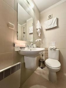 a bathroom with a sink and a toilet and a mirror at Spacious penthouse chalet apartment in Pirin Golf and Country Club in Razlog