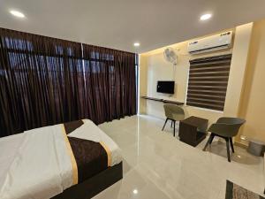 Dormitorio con cama, escritorio y TV en THAAL RESIDENCY Cheruvathur-HALA GROUPS en Nīleshwar
