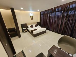a bedroom with a bed and a chair in it at THAAL RESIDENCY Cheruvathur-HALA GROUPS in Nīleshwar