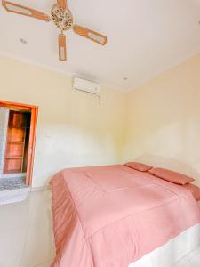 a bedroom with a pink bed and a ceiling fan at Ojek's Homestay in Ubud