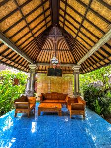 a living room with a couch and chairs under a wooden roof at Ojek's Homestay in Ubud
