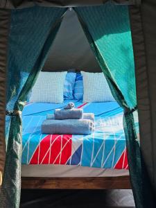 a bed in a tent with towels on it at Merry Mongoose Riverside Tent in Skeerpoort