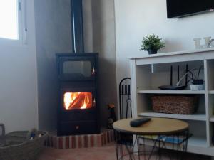 a living room with a stove with a table and a table at LAS TRES ROSAS in Vejer de la Frontera