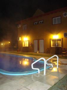 a swimming pool at night with lights in front of a house at Cabañas Ensueño del Lago in Termas de Río Hondo