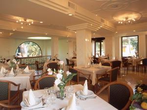 un ristorante con tavoli e sedie bianchi con fiori di Albergo Villa Hibiscus a Ischia